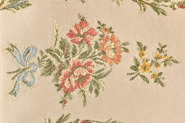 detail of the embroidery of a brocade fabric with a yellow floral motif in relief on a beige base © Adriano