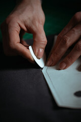 Detailed close-up photograph showing hands guiding fabric through an industrial sewing machine. The image captures the precision and craftsmanship involved in textile production and tailoring. Ideal f