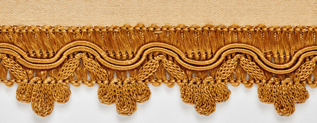 detail of silk trimmings for furniture, ochre color, classic style on white background
