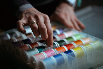 Detailed close-up photograph showing hands guiding fabric through an industrial sewing machine. The image captures the precision and craftsmanship involved in textile production and tailoring. Ideal f