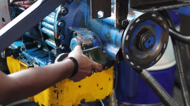 Close up technician hand holding a digital tachometer, and measuring the rotation of the output flange of the automatic transmission, test bench transmission.