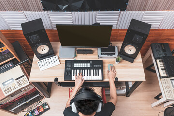 top view of asian male music producer, composer, arranger, musician composing a song in home recording studio. music production concept
