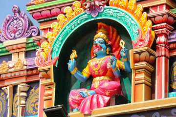 Dog-faced goddess resembling Kali with four arms and protruding tongue, Dravidian style temple roof niche sculpture, Hindu mythology