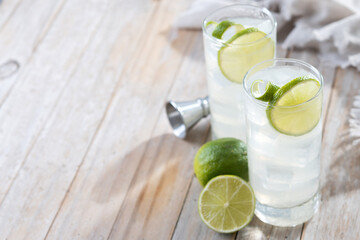 Gin Fizz cocktail with lime on wooden table. Copy space