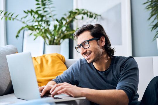 Smiling man using laptop while studying at home