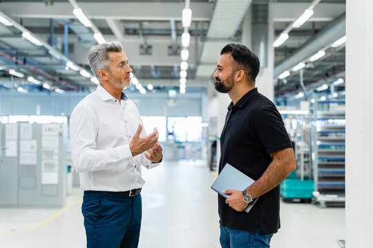 Businessman explaining maintenance engineer at automated industry