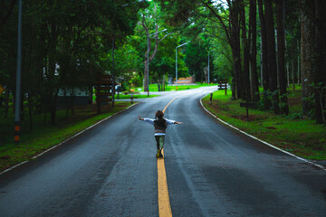 Happy little girl tourist walking on asphalt road outdoors enjoying beautiful nature of forest in national park on spring vacation.