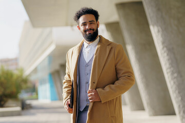 A Stylish Man in a WellFitted Overcoat is Posing Confidently Outdoors Against a City Backdrop