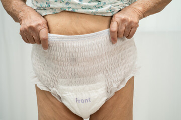 Asian senior woman patient wearing adult incontinence diaper pad in hospital.