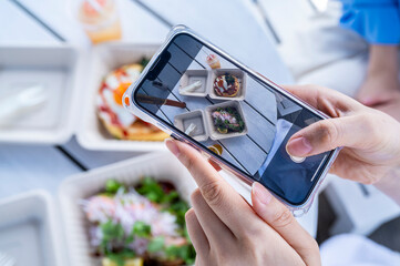Close-up of hands photographing a healthy meal for social media at a seaside café