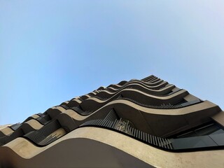 Low angle view of modern curved high rise building. Curvy Facade of skyscraper. Office building against blue sky. Contemporary architectural design  © yassine
