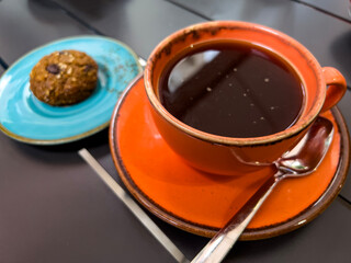 Black coffee and cookies in colourful vintage dishes