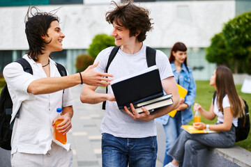 Two cheerful male students talking and walking on university campus