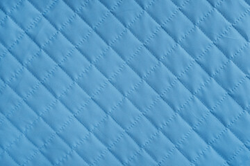 Obraz premium Checkered, diamond stitching pattern, blue quilted fabric background. Blanket or puffer jacket, stitch rhombus texture close up, macro. Wallpaper, backdrop.