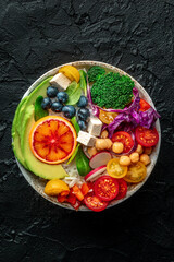Buddha Bowl. Rainbow salad. Vegan poke bowl with avocado. Healthy food. Top shot on a black stone background