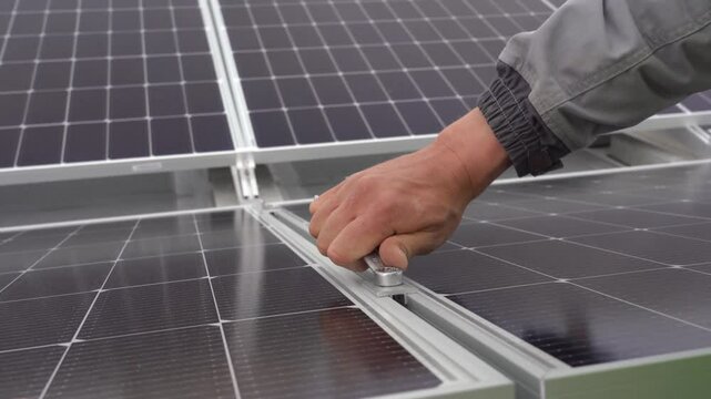 A worker secures solar panels to a frame.