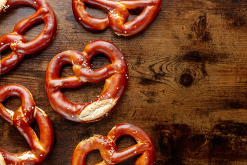Pretzel or Bretzel, traditional German beer snack, a salty wheat bread, overhead flat lay shot on a wooden background with copy space, a pattern