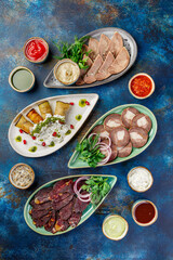 The bowls are filled with different kinds of food, including various meat appetizers, vegetable appetizers, and sauces. A table with many bowls of food on it.