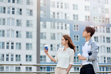 Fototapeta premium Young Asian Man and Woman Relaxing Outdoors with Coffee in Urban Cityscape