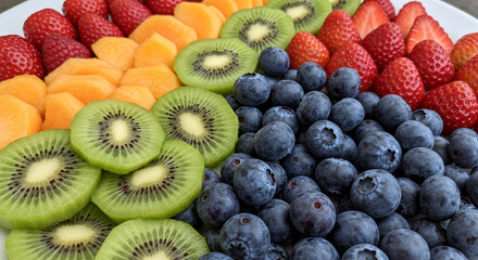 Obraz premium A colorful fruit platter featuring strawberries cantaloupe kiwi and blueberries arranged together nicely