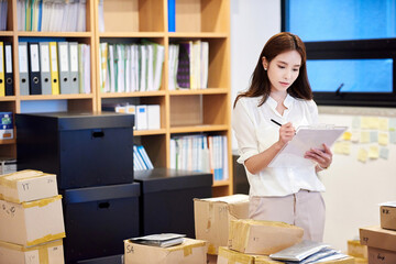 Young Asian Woman Inventory Manager Checking Parcels in Modern Office