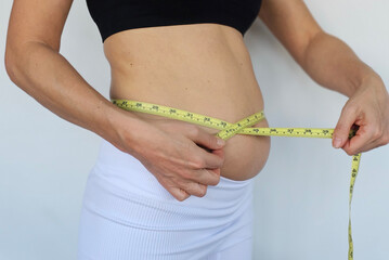 Pregnant individual measuring belly with tape for health updates pregnancy journey