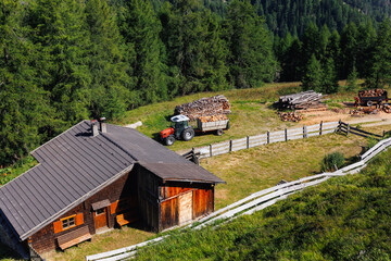 Scenic aerial view alpine village log wooden countryside cabin lumber stock lumber timber manufacture yard tractor machinery and storage. Rural landscape meadow wood piles forestry country vibe