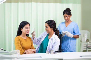 Fototapeta premium Facial aesthetics surgery treatment : Plastic (Cosmetic) Surgery Center : Brazilian hispanic female Doctor preparing Asian female patient for cosmetic surgery in clinic