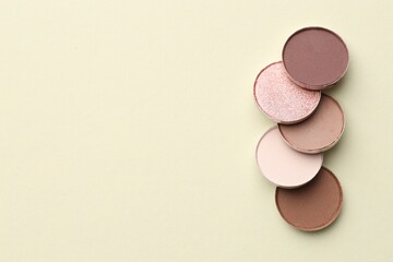 Beautiful eyeshadow refill pans on beige background, flat lay. Space for text