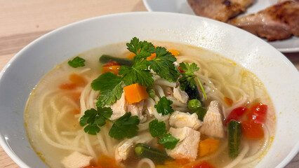 Warm noodle broth featuring vibrant veggies evokes Lunar New Year dining, rich umami delight with fresh cilantro garnish