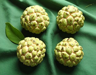 Obraz premium Fresh Cherimoya Fruits on Green Fabric Background Closeup Shot of Four Exotic Fruits