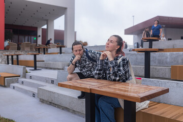 Modern seating zone with clean lines. Woman daydreams with chin on hands, man watches thoughtfully. Muted color palette, casual wear, architectural harmony.