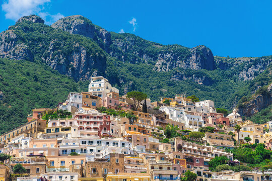 Explore the stunning cliffside village of Positano in Amalfi Coast Italy, featuring colorful buildings nestled against the dramatic mountains and lush greenery.