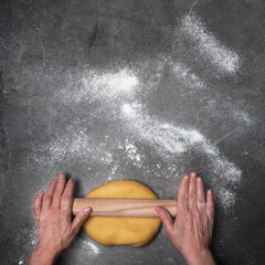 Caucasian hands rolling dough on floured board flat lay view with copy-space