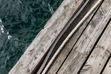 Weathered wooden pier with coiled rope and ocean water