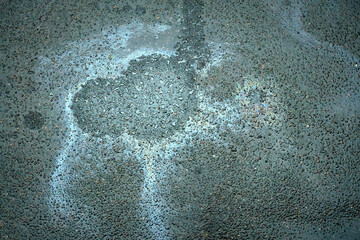 Abstract shapes created by a gasoline spill on the wet asphalt, reflecting the colors of the rain-soaked surface