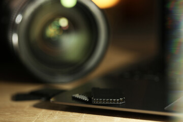 SD memory cards, laptop and photo camera on wooden table, closeup