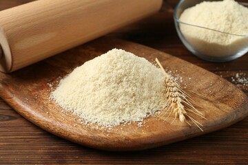 Pile of flour, spike and rolling pin on wooden table, closeup