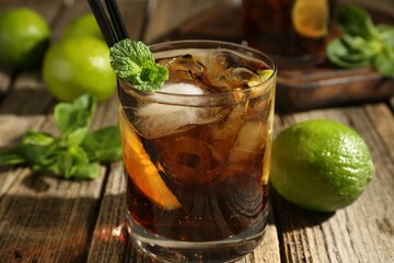 Refreshing Cuba libre cocktail with mint on wooden table, closeup