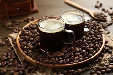 Aromatic coffee in cups and beans on wooden table, closeup