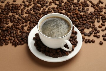 Aromatic coffee in cup and beans on beige background, above view