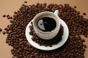 Aromatic coffee in cup and beans on beige background, above view