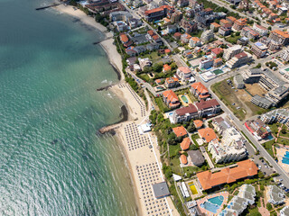 Aerial view of Sveti Vlas, a Bulgarian seaside resort town with a marina, beaches, red-roofed buildings, and green hills. Popular summer destination on the Black Sea coast