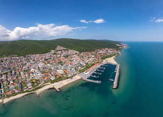 Panoramic aerial view of Sveti Vlas, Bulgaria, showing the marina, beaches, red-roofed buildings, and lush green hills along the Black Sea coast. Popular summer resort town