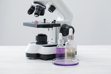 Making luxury perfume. Essential oils in glassware and microscope on white wooden table, closeup