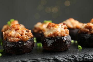 Tasty stuffed mushrooms served on black table against blurred background, closeup