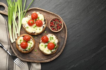 Tasty stuffed mushrooms served on black table, flat lay. Space for text