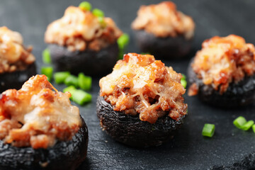 Tasty stuffed mushrooms served on black table, closeup