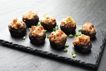 Tasty stuffed mushrooms served on black table, closeup