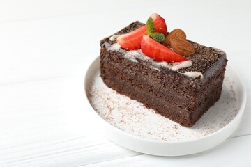 Piece of delicious chocolate cake with strawberry and almonds on white wooden table, closeup. Space for text